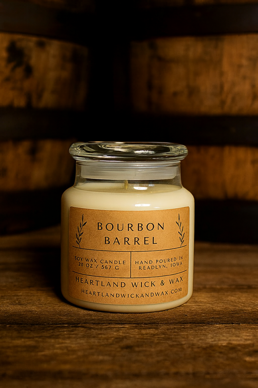 Candle in a glass jar labeled 'Bourbon Barrel' on a wooden surface with a wooden background.